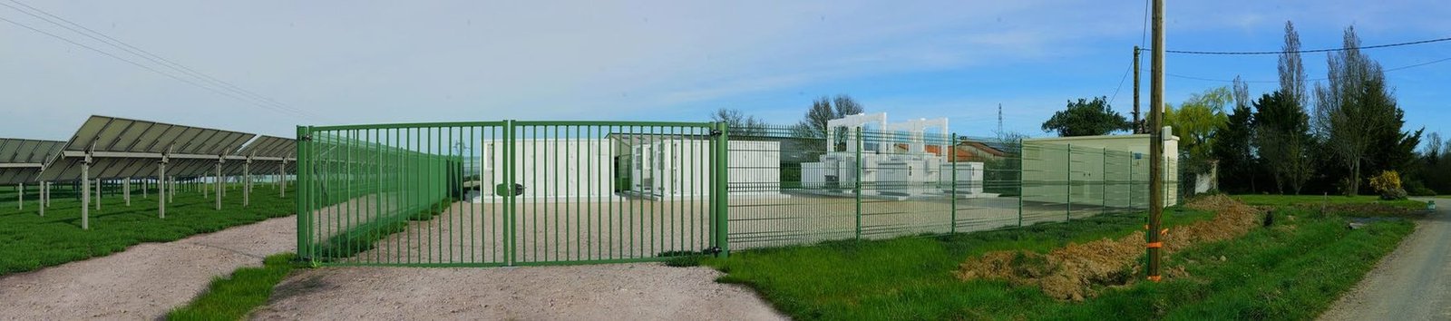 Photomontage du portail, de la clôture et des conteneurs de stockage d’une centrale photovoltaïque en bord de voie
